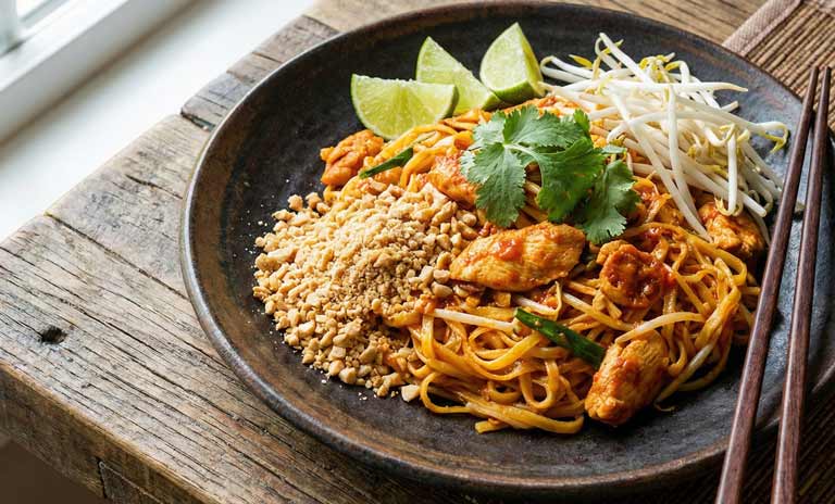 Assiette de pad thaï avec quartiers de lime et arachides concassées